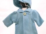 une poupée qui porte un manteau bleu et un chapeau