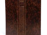 an old book with a brown cover sitting on top of a white surface