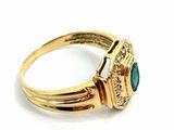 a close up of a gold ring with a green stone