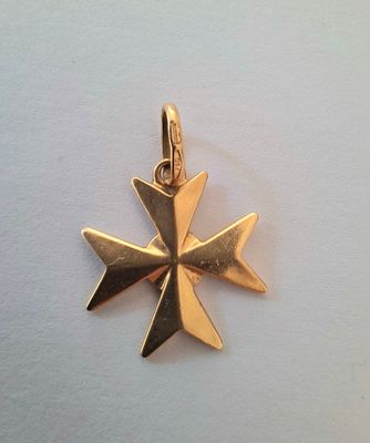 a close up of a gold cross pendant on a white surface
