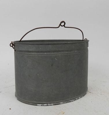 an old metal bucket sitting on top of a white surface
