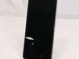 a black cell phone sitting on a stand on a white surface