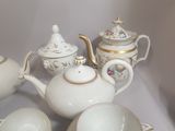 a white tea pot with a gold trim and a tea cup and saucer