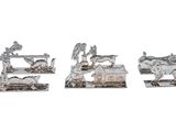 three silver figurines of animals on a white background