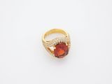 a yellow gold ring with a red stone surrounded by diamonds
