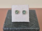 a pair of green earrings sitting on top of a black box