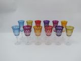 six different colored wine glasses lined up on a white surface