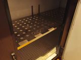 un petit réfrigérateur dont la porte est ouverte, posé sur un sol carrelé