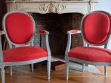 two red chairs in front of a fireplace in a room
