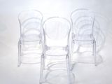 three clear plastic chairs sitting next to each other on a white surface