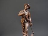 bronze statue of a man with a cane and hat on a wooden base