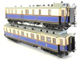 two blue and white trains sitting side by side on a white surface