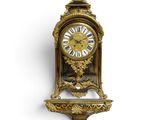 une horloge dorée sur un mur blanc, avec un fond blanc