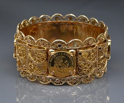 a close up of a gold bracelet with a coin on it