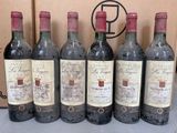 six bouteilles de vin sont alignées en rang devant une boîte en carton