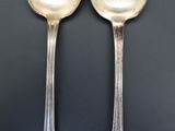 two silver spoons sitting next to each other on a table