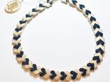 Le collier est en cuir bleu et blanc, avec un fermoir plaqué or.