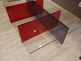a glass table with a red glass top on a tiled floor