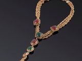 un collier en or orné de pierres vertes et roses sur fond noir