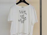 un t-shirt blanc orné de papillons noirs, suspendu à un cintre