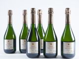 six bottles of champagne lined up in a row on a white surface