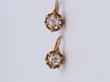 une paire de boucles d'oreilles en or sur une surface blanche