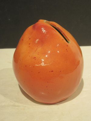 un petit vase orange posé sur une table blanche