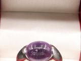 une photo d'une bague sertie d'une pierre violette, dans un écrin
