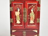 a small red cabinet with two asian figures on it