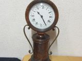 a small clock sitting on top of a table next to a pink flower