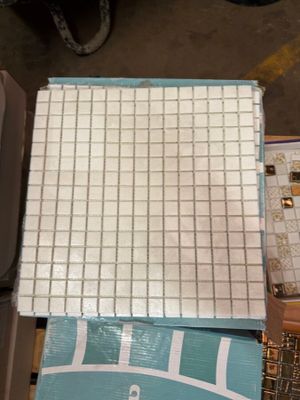 a pile of tile on the floor next to a box of toilet paper