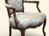 une chaise dont le dossier est recouvert d'un tissu à motifs floraux et dont la structure est en bois