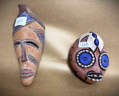 two masks that are sitting on a leather surface