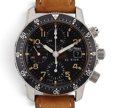 the watch has a black dial and a brown leather strap