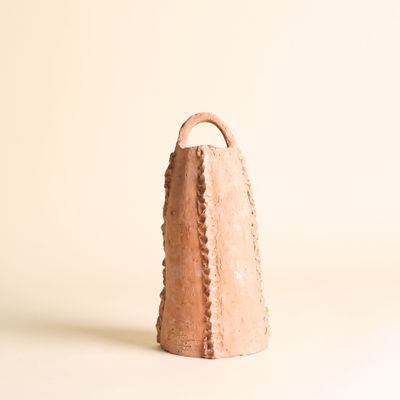 une cloche en argile posée sur une surface blanche