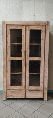 une armoire en bois avec des portes vitrées, posée sur un sol carrelé