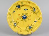yellow plate with blue and yellow flowers on it on a stand