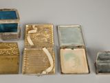 several small silver and gold jewelry boxes sitting on top of a white table