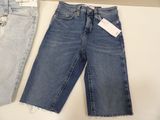 two pairs of jeans are on a shelf next to a hanger