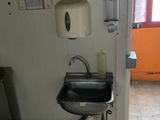 a sink in the corner of a room with a lot of papers on the wall