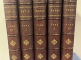 six vieux livres sont alignés sur une nappe bleue