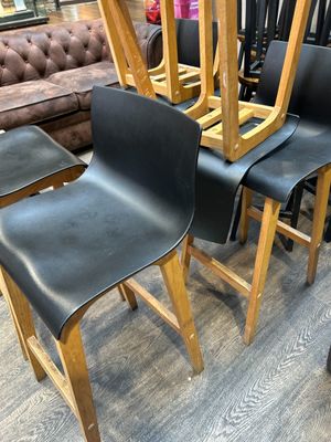 quatre chaises en cuir noir sont empilées dans un magasin