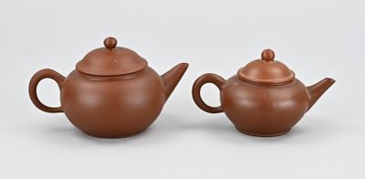 deux théières en céramique marron, munies d'un couvercle, sont posées sur une surface blanche