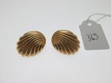 une paire de boucles d'oreilles en or en forme de coquillage posées sur un fond blanc
