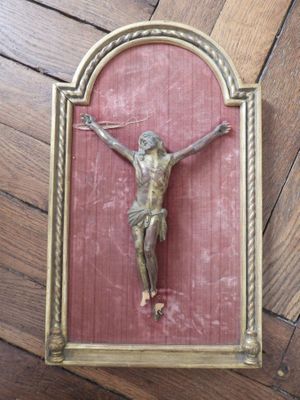 un crucifix en or sur un mur rouge, devant un parquet