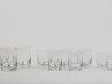 six shot glasses lined up in a row on a white surface