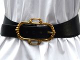 une ceinture noire avec une boucle dorée sur un mannequin