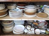 de nombreuses assiettes et bols empilés sur une étagère dans un placard