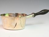 a silver sauce pot with a black handle on a white table