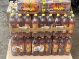 Des bouteilles de jus d'orange sont empilées sur une palette dans un entrepôt